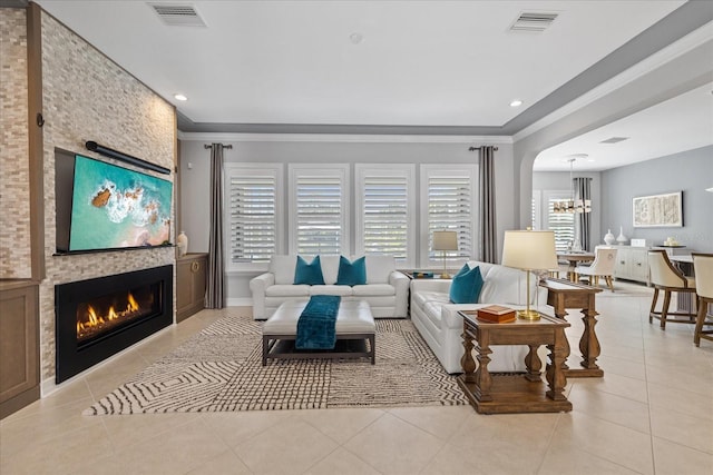 tiled living room featuring a fireplace, an inviting chandelier, and crown molding