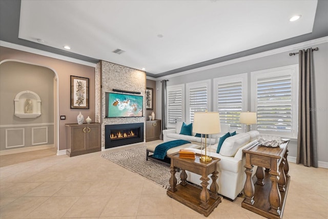 tiled living room featuring crown molding and a fireplace