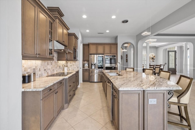 kitchen with appliances with stainless steel finishes, a kitchen breakfast bar, sink, hanging light fixtures, and a large island