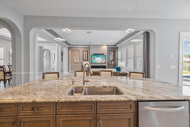 kitchen featuring decorative light fixtures, light stone counters, plenty of natural light, and sink