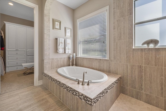 bathroom featuring tile patterned flooring and a relaxing tiled tub