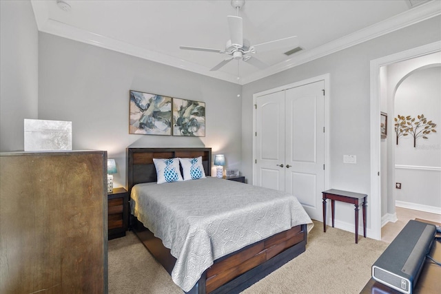 bedroom featuring light carpet, a closet, ceiling fan, and crown molding