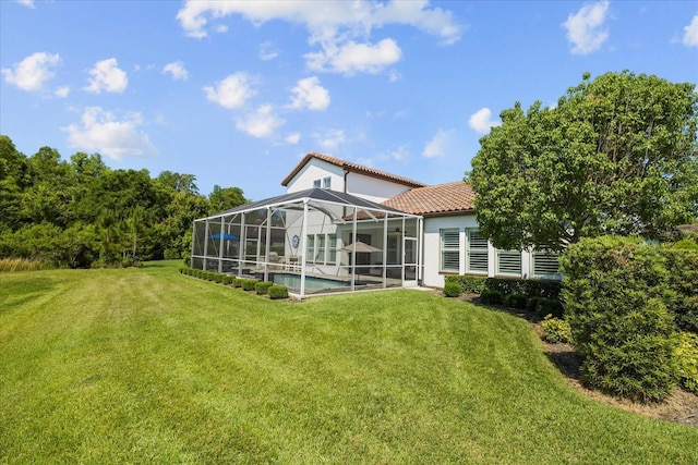 back of house with a lawn and glass enclosure