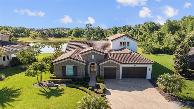 mediterranean / spanish home with a front lawn, a water view, and a garage