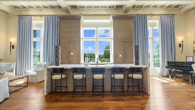 kitchen with wood-type flooring, a breakfast bar area, and beam ceiling