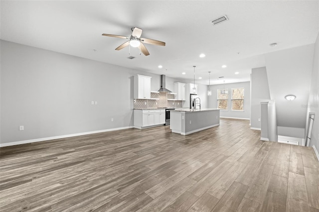 unfurnished living room featuring wood-type flooring, ceiling fan, and sink