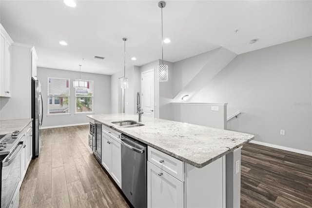 kitchen featuring appliances with stainless steel finishes, sink, a center island with sink, white cabinets, and hanging light fixtures