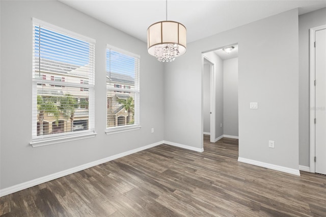 empty room with a chandelier and dark hardwood / wood-style flooring