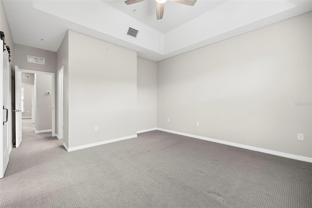 empty room featuring carpet flooring, a barn door, and ceiling fan