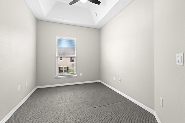 empty room featuring a tray ceiling, ceiling fan, and carpet