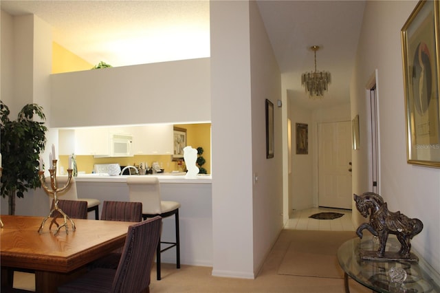 hallway featuring light tile patterned floors, a towering ceiling, and an inviting chandelier