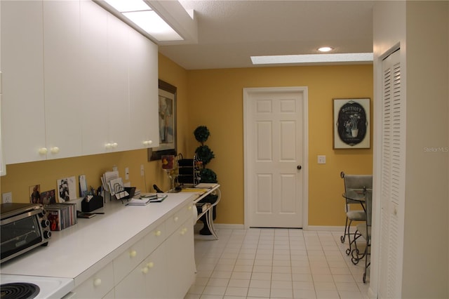 kitchen with white cabinets, light tile patterned flooring, and range