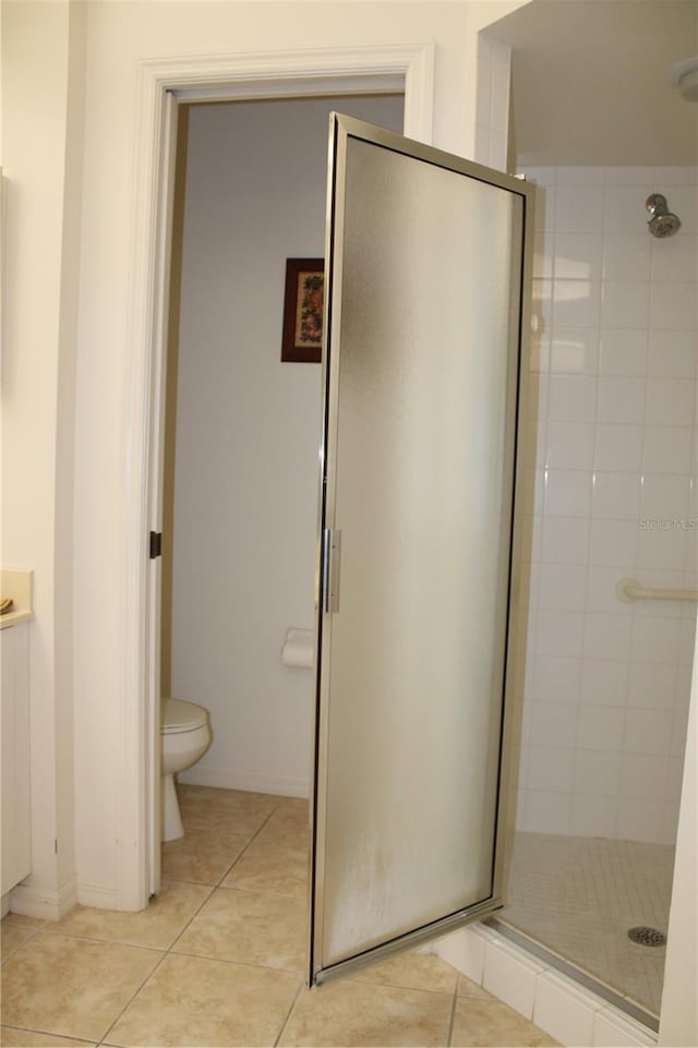 bathroom with toilet, a shower with door, and tile patterned flooring