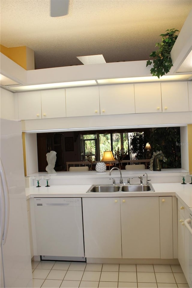 kitchen with white dishwasher, sink, white cabinetry, and light tile patterned floors