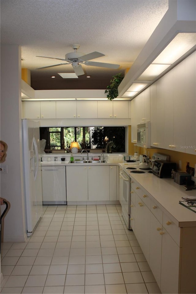 kitchen featuring white appliances, white cabinetry, sink, ceiling fan, and light tile patterned floors