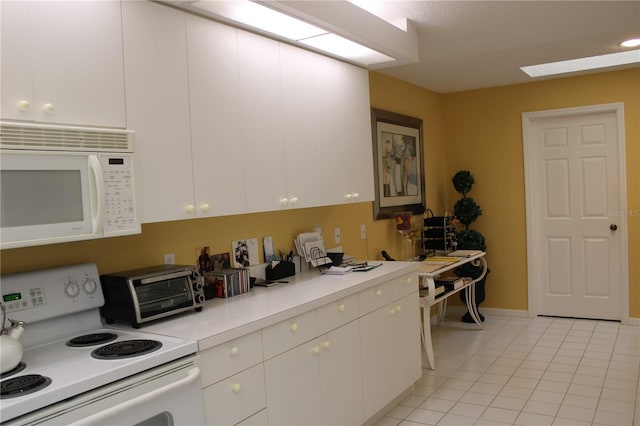 kitchen with white cabinets, light tile patterned floors, and white appliances