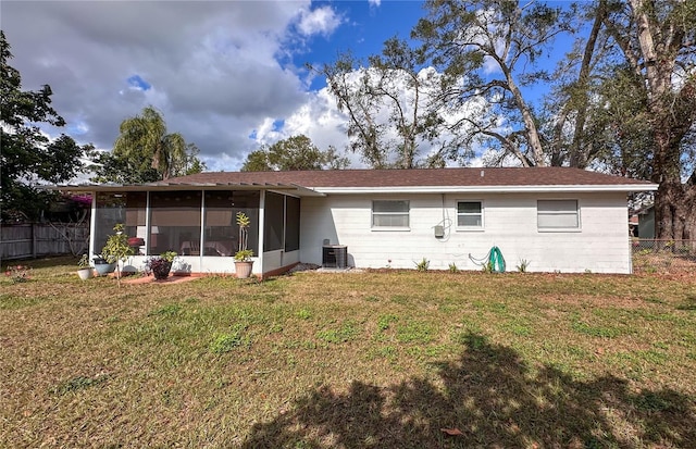 rear view of property featuring a sunroom, cooling unit, and a lawn