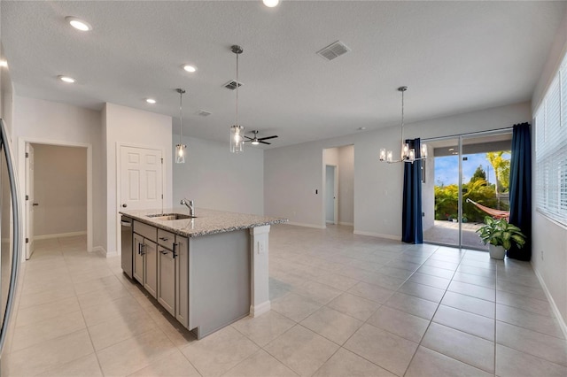 kitchen featuring dishwasher, sink, light stone counters, a center island with sink, and ceiling fan with notable chandelier