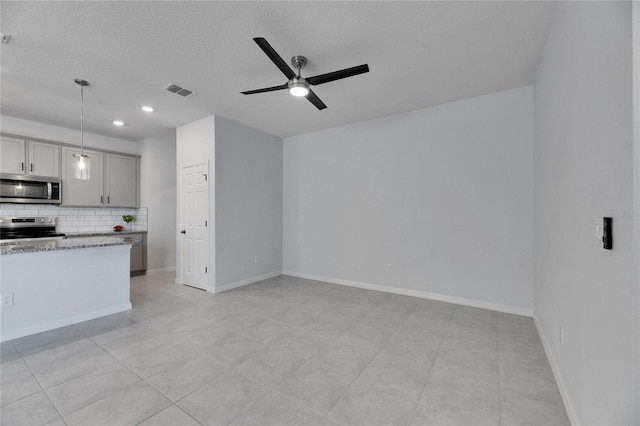 kitchen featuring gray cabinetry, hanging light fixtures, backsplash, stove, and light tile patterned floors