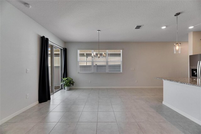 unfurnished dining area featuring light tile patterned floors, a textured ceiling, and a notable chandelier