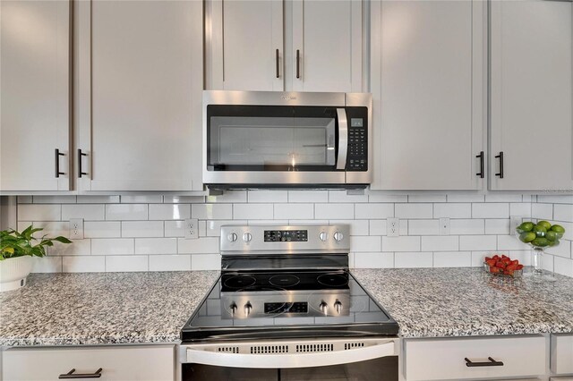 kitchen with decorative backsplash, light stone counters, and stainless steel appliances