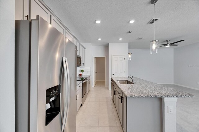 kitchen with sink, ceiling fan, light stone countertops, decorative light fixtures, and stainless steel appliances