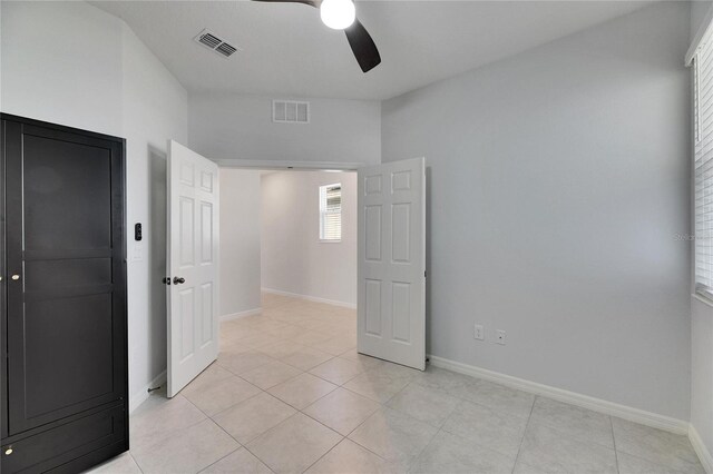 empty room with ceiling fan and light tile patterned floors