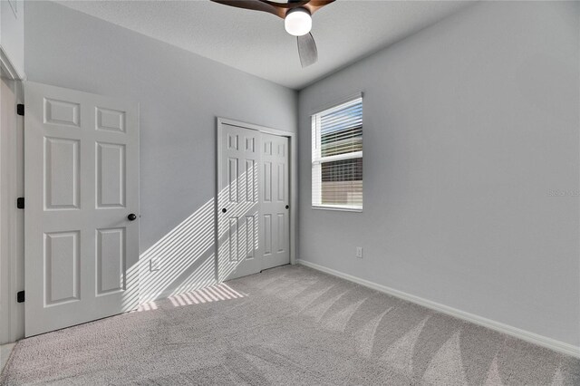 unfurnished bedroom with ceiling fan, a closet, and light carpet