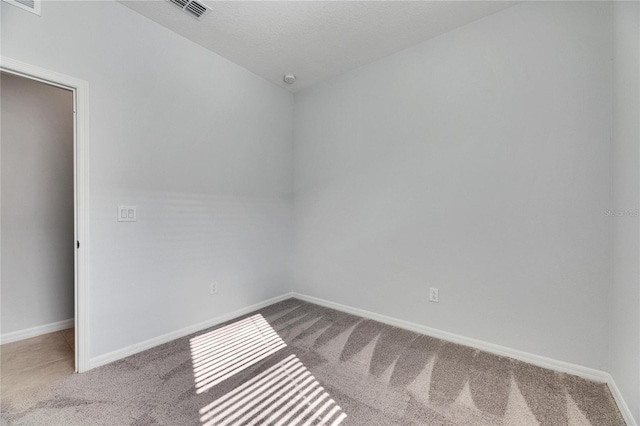 spare room featuring light carpet and a textured ceiling