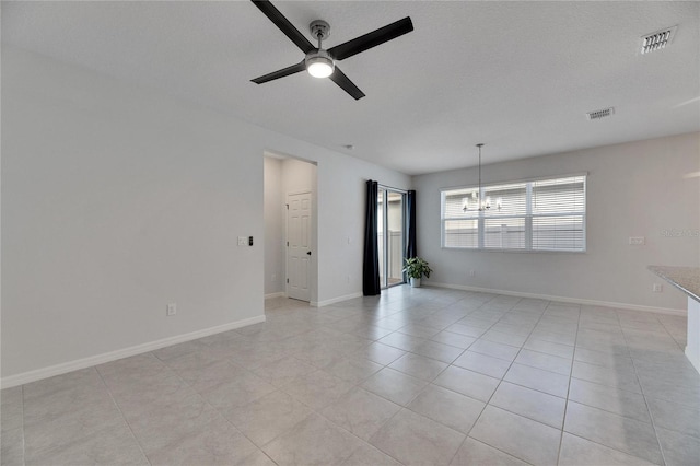 tiled spare room with ceiling fan with notable chandelier and a textured ceiling