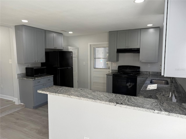 kitchen featuring black appliances, gray cabinets, light stone countertops, light hardwood / wood-style floors, and kitchen peninsula