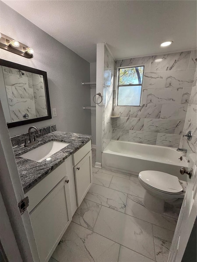 full bathroom with vanity, toilet, a textured ceiling, and tiled shower / bath combo