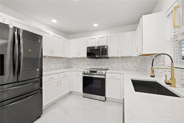 kitchen with tasteful backsplash, sink, white cabinets, and stainless steel appliances