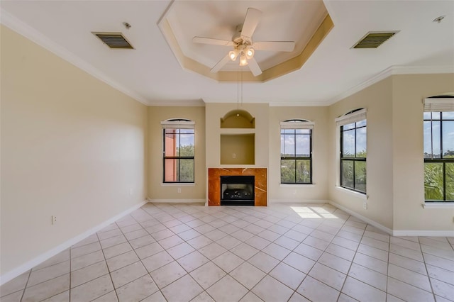 unfurnished living room featuring light tile patterned floors, ceiling fan, a tray ceiling, and ornamental molding