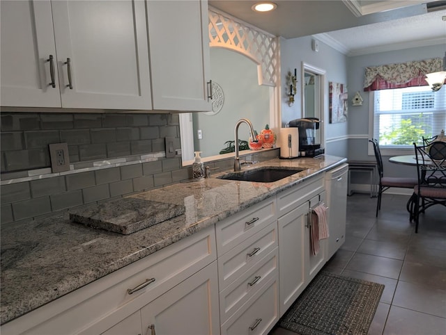 kitchen featuring light stone countertops, tasteful backsplash, white dishwasher, sink, and white cabinets