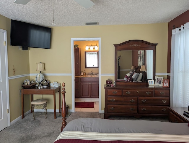 tiled bedroom with visible vents, carpet flooring, connected bathroom, a sink, and a textured ceiling