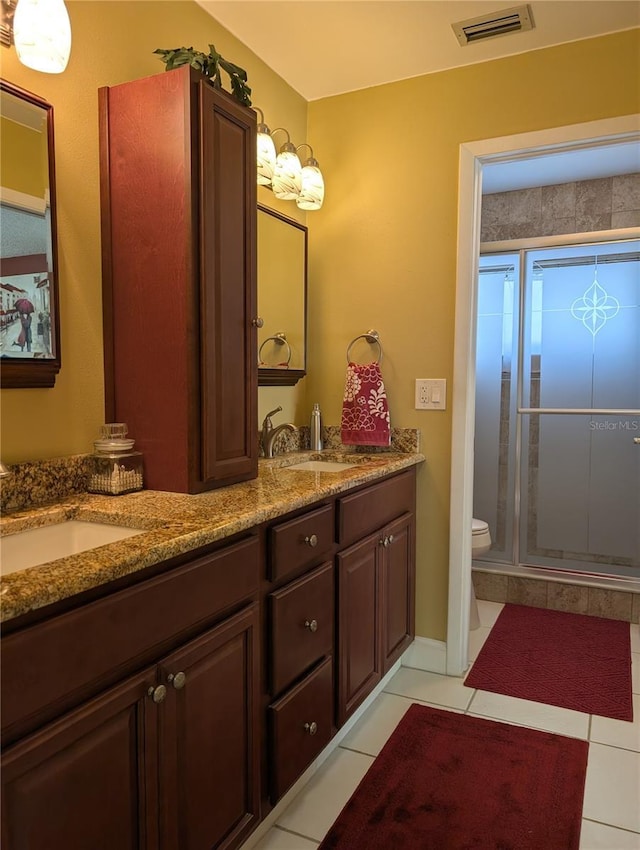 bathroom with tile patterned flooring, vanity, toilet, and a shower with door