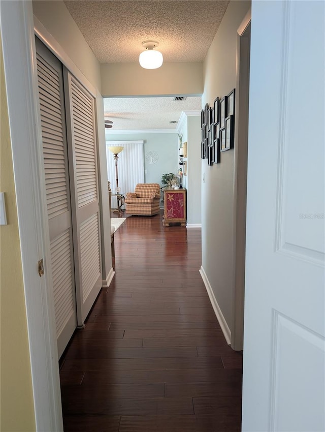 corridor featuring dark wood-style floors, baseboards, and a textured ceiling