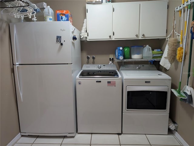 clothes washing area featuring washing machine and clothes dryer, light tile patterned floors, and cabinets