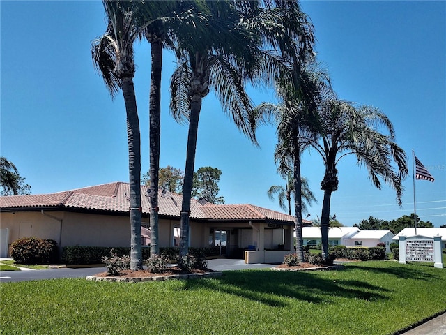 view of front of property featuring a tiled roof, a front yard, and stucco siding