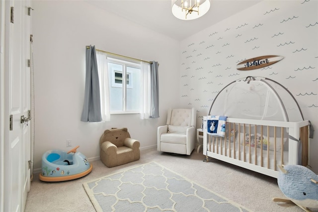 bedroom featuring an inviting chandelier, carpet flooring, and a crib