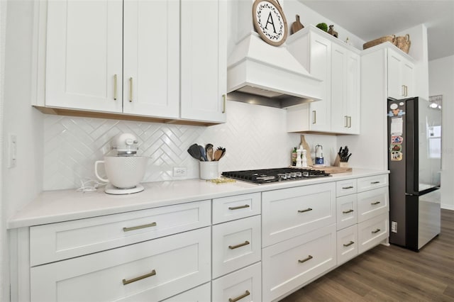 kitchen with appliances with stainless steel finishes, dark hardwood / wood-style floors, tasteful backsplash, white cabinets, and custom range hood