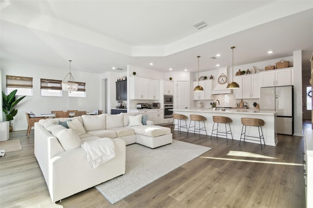 living room with light hardwood / wood-style floors, sink, and a notable chandelier