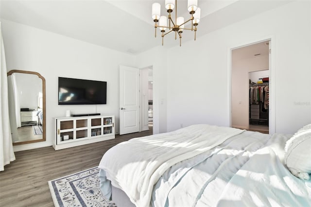 bedroom featuring a notable chandelier, a spacious closet, dark wood-type flooring, and a closet