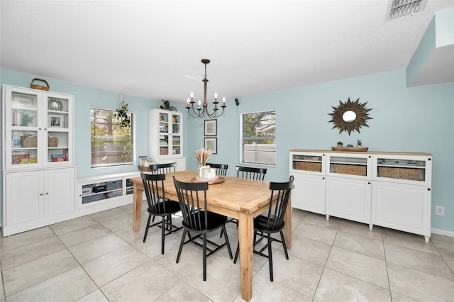 tiled dining area with a textured ceiling and a notable chandelier