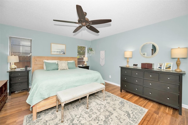 bedroom with ceiling fan, light hardwood / wood-style flooring, and a textured ceiling