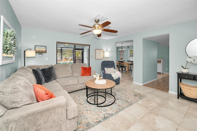 tiled living room featuring ceiling fan with notable chandelier and a textured ceiling