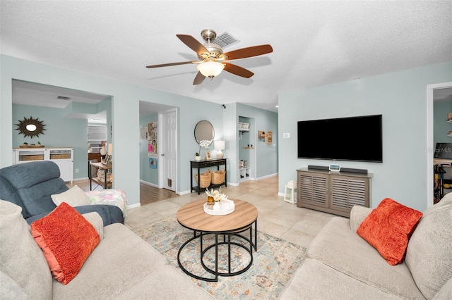 living room with ceiling fan, tile patterned flooring, and a textured ceiling