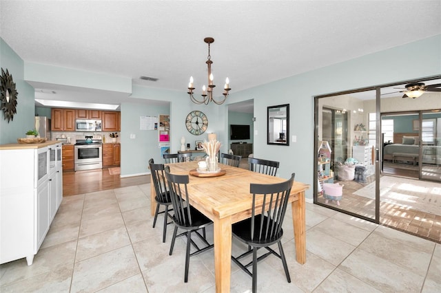 dining room featuring a textured ceiling, ceiling fan with notable chandelier, and light tile patterned flooring