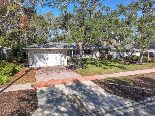 single story home featuring a front lawn, decorative driveway, and an attached garage